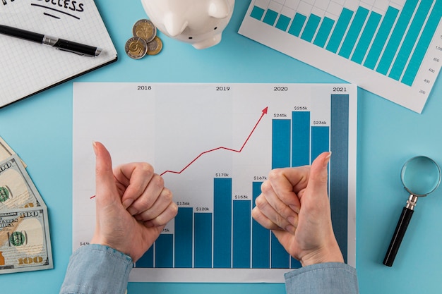 Top view of business items with growth chart and hands giving thumbs up